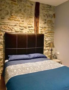 a bedroom with a blue bed with a stone wall at Doma Etxea Donostia-San Sebastian in San Sebastián
