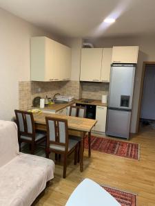 a kitchen with a table and chairs and a refrigerator at Comfortable apartment close to the city center in Prishtinë