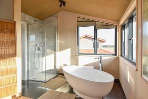 ein Badezimmer mit einer großen weißen Badewanne und einer Dusche in der Unterkunft Hotel Gutshaus Parin - Bio- und Gesundheitshotel in Parin