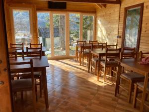 a dining room with tables and chairs and windows at Bujtina Arturi in Valbonë