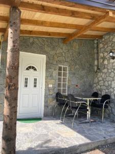 a patio with a table and chairs and a white door at Bujtina Arturi in Valbonë