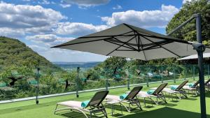 a group of chairs and an umbrella on a lawn at Verkhovyna Resort Medical & Wellness in Kamenitsa