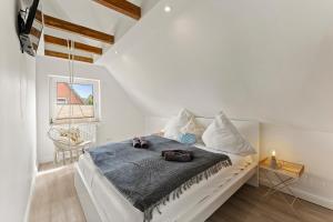 a white bedroom with a bed with a blue blanket at Huus Frieda in Krummhörn