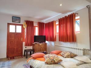 two beds in a bedroom with red curtains and a television at Summit Apartment in Žabljak