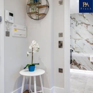 a small white stool with a plant on it next to a bathroom at Pluxa Larimar - Spacious Apt with Private Entrance, Workspace & Wi-Fi in Harrow