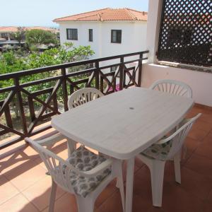 uma mesa branca e cadeiras numa varanda em Tortuga Beach Village Private Apartments and Villas for Rent em Santa Maria