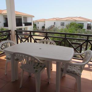 uma mesa branca e cadeiras numa varanda em Tortuga Beach Village Private Apartments and Villas for Rent em Santa Maria