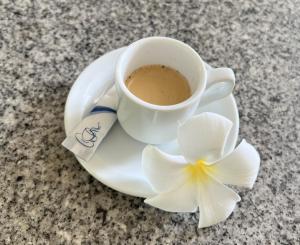 a cup of coffee and a flower on a plate at Pare LODGE TAHITI in Pirae