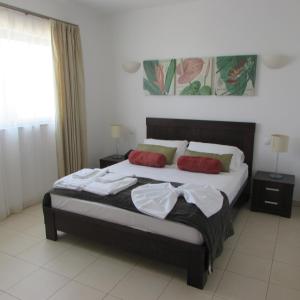 a bedroom with a large bed with two red pillows at Tortuga Beach Village Private Apartments and Villas for Rent in Santa Maria