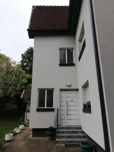 Casa blanca con puerta y escaleras en Kuća JEKA en Vrnjačka Banja