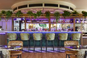 - un bar avec des tables et des chaises dans une salle à l'éclairage violet dans l'établissement Leonardo Royal Southampton Grand Harbour, à Southampton