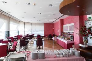 un restaurante con paredes rosas, mesas y sillas en Hotel Pombalense, en Pombal