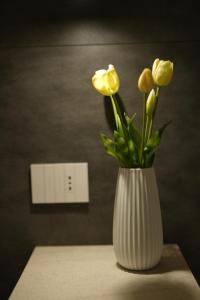 a white vase with yellow flowers sitting on a table at Enea Suite in Trapani