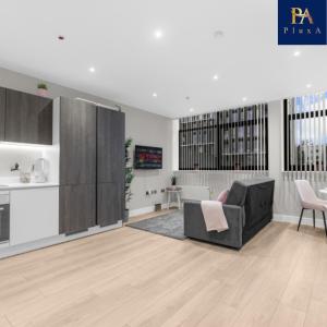 a living room with a couch and a kitchen at Pluxa Blush - Blush Gem with Private Entrance, Workplace, Harrow Haven in Harrow