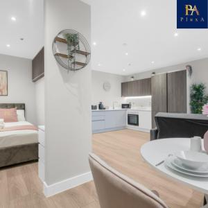 a bedroom and a living room with a bed and a table at Pluxa Blush - Blush Gem with Private Entrance, Workplace, Harrow Haven in Harrow
