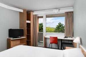 um quarto de hotel com uma cama, uma secretária e uma janela em Ibis Budapest Citysouth em Budapeste