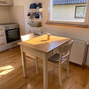 a kitchen with a wooden table and two chairs at Esther in Norddorf