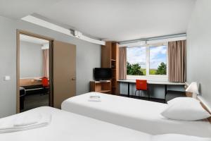 um quarto de hotel com duas camas, uma secretária e um espelho em Ibis Budapest Citysouth em Budapeste