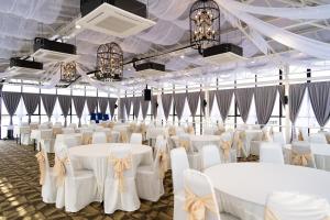 a banquet hall with white tables and chairs and chandeliers at RM Hotel in Muar