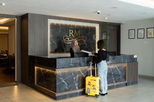 a woman with a yellow suitcase standing at a counter at RM Hotel in Muar