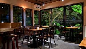 um restaurante com mesas e cadeiras e janelas grandes em Shinkyo Inn em Nikko