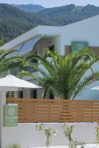 a building with a fence and palm trees in front of it at Essentia Vita Comfy Suites in Limenas