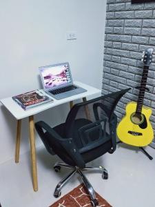 escritorio con ordenador portátil y silla con guitarra en Arthomes BB6, en Mandaue