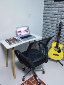 a desk with a laptop and a chair with a guitar at Arthomes BB6 in Mandaue City
