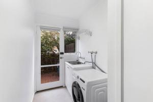 a white laundry room with a sink and a washing machine at A Home away from home in Geelong in Geelong