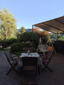 una mesa con sillas y una sombrilla en el patio en Il Glicine appartamento vacanze, non solo mare!, en Casarza Ligure