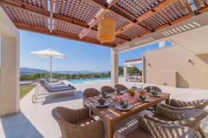 - une salle à manger avec une table, des chaises et une piscine dans l'établissement Carpe Diem Villa - Luxurious, 15km From The Beach, à Vederoi
