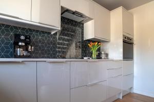 a kitchen with white cabinets and black tiles at B’s house in Simpson