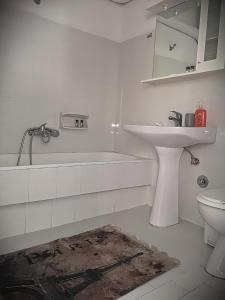 a white bathroom with a sink and a toilet at Centrally Apartments in Xanthi
