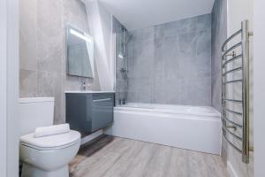 a bathroom with a toilet and a tub and a sink at Stylish, Central and Spacious Apartments in Southport in Southport