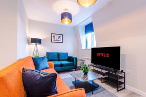 a living room with a couch and a tv at Stylish, Central and Spacious Apartments in Southport in Southport