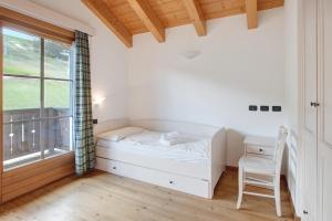 a bedroom with a bed and a desk and a window at Baita Valandrea 3 in Livigno
