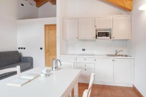 una cocina con armarios blancos y una mesa con sillas. en Baita Valandrea 3, en Livigno