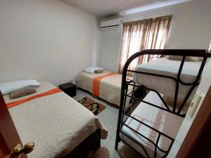 1 Schlafzimmer mit 2 Etagenbetten und einem Fenster in der Unterkunft Aptos Casa Caribe, habitaciones privadas en aptos compartidos & aptos completos con auto entrada in Puerto Limón