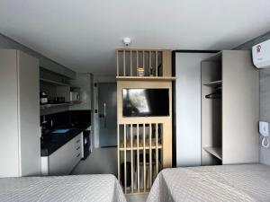 een kamer met 2 bedden en een keuken met een televisie bij Flat Gold Get One - João Pessoa in João Pessoa