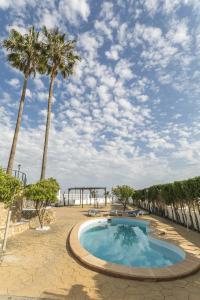 a swimming pool with palm trees and a playground at Villa Los Leones Nerja in Nerja