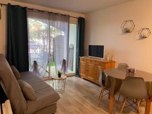 uma sala de estar com um sofá, uma mesa e uma televisão em Appartement T2 à 900m du Bassin d Arcachon em Arès