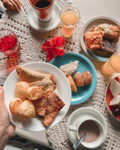 uma mesa coberta com pratos de alimentos e bebidas ao pequeno-almoço em Pousada Morro dos Navegantes em Ilhéus