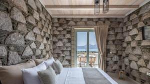 una camera da letto con un muro in pietra e un letto con cuscini di Thea Sunset Suites a Mytakas