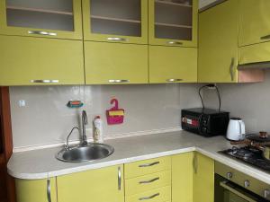 a kitchen with yellow cabinets and a sink at Квартира з видом на Дніпро in Cherkasy