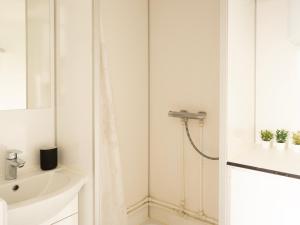 uma casa de banho branca com um chuveiro e um lavatório. em Cozy Container Rental - 3BR - 20 min to capital em Strendur
