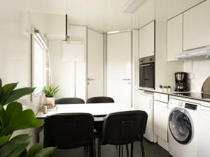 uma cozinha branca com uma mesa e cadeiras pretas em Cozy Container Rental - 3BR - 20 min to capital em Strendur