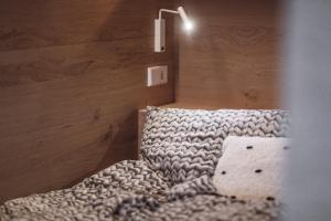 a bedroom with a bed with a light on the wall at Rousa little guesthouse Cosy Plus in Rasun di Sopra