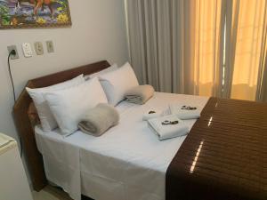 a bed with white sheets and pillows on it at Salata Hotel in Jardinópolis