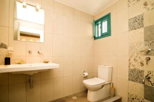 a bathroom with a toilet and a sink and a mirror at SUITES DREAM TELENDOS in Kalymnos