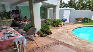 un patio con una mesa y una piscina en Villa Roc Guesthouse - Solar Power, en Ballito